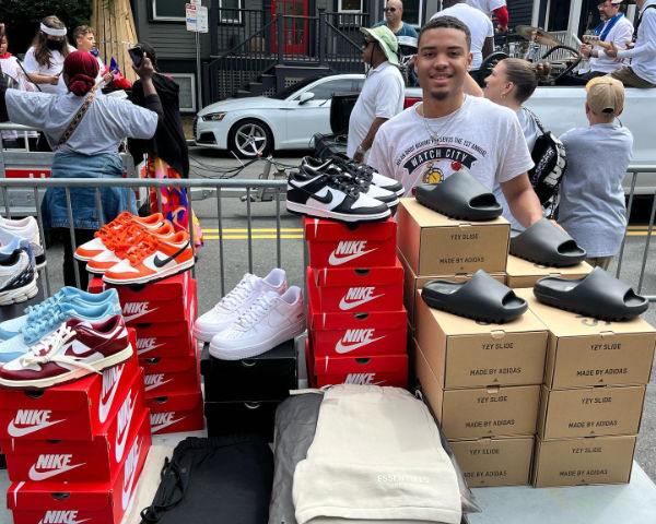man standing next to boxes of shoes